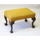 A CHIPPENDALE STYLE MAHOGANY FOOTSTOOL, with padded top, on cabriole legs ending in claw and ball