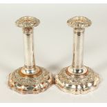 A SMALL PAIR OF PLAIN COLUMN PLATED CANDLESTICKS, on shaped bases. 18cms high.