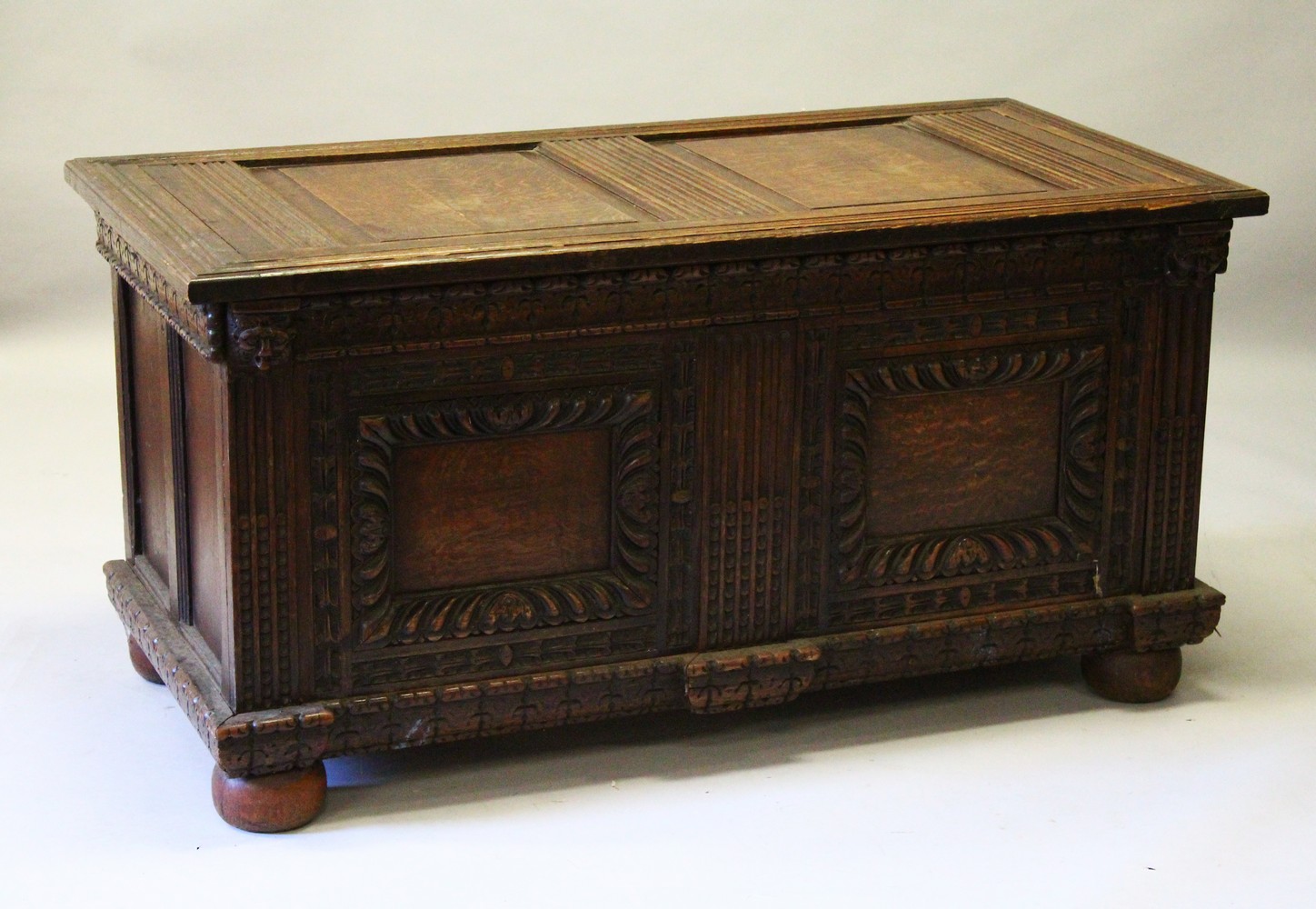 A LARGE 17TH-18TH CENTURY FRENCH OAK COFFER, with two plain panels to the top and two carved