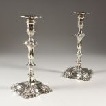 A PAIR OF EDWARD VII SILVER CANDLESTICKS on loaded bases. Crested. 24cms high.