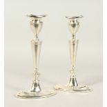 A PAIR OF ADAM DESIGN PLATED CANDLESTICKS. 21cms high.