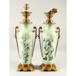 A PAIR OF JAPANESE MEIJI PERIOD CELADON GROUND MOULDED PORCELAIN VASES / LAMPS, the bodys of the