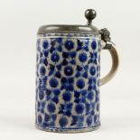 A WESTERWALD POTTERY TANKARD, with pewter cover, the body with blue design. 20cms high.