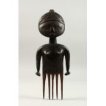 A VERY GOOD CARVED WOOD TRIBAL COMB, as a standing female figure. 27cms.