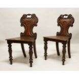 A GOOD PAIR OF REGENCY MAHOGANY HALL CHAIRS, with shaped backs, solid seats, on turned legs.