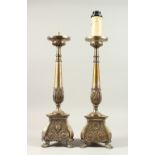A PAIR OF METAL CANDLESTICKS, on circular bases converted to lamps. 52cms high.