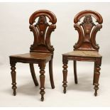 A GOOD PAIR OF LATE REGENCY MAHOGANY HALL CHAIRS, with shaped backs, solid seats, on turned legs.