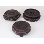 THREE 19TH CENTURY CHINESE CARVED WOOD VASE STANDS. 20cms, 16cms and 15cms diameter.