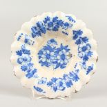 AN 18TH CENTURY DELFT BLUE AND WHITE CIRCULAR SHAPED PLATE, decorated with flowers in blue. 21cms