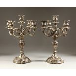 A PAIR OF ROCOCO STYLE FOUR BRANCH, FIVE LIGHT CANDELABRA, with embossed and chase decoration, the