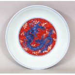 A CHINESE TIBETAN MARKET COPPER-RED & UNDERGLAZE-BLUE DRAGON SAUCER DISH, its outer rim with a