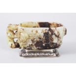 A CHINESE 18TH CENTURY CARVED JADE LIBATION CUP, the sides carved with animals and scrolls, on a
