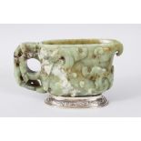 A CHINESE 18TH CENTURY CARVED JADE LIBATION CUP, the sides carved with animals and scrolls, on a