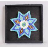 A FINE 17TH CENTURY OR EARLIER PERSIAN STAR SHAPED MOSAIC TILE, 21cm on a wooden surround.