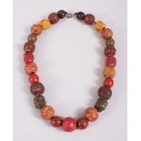 A JAPANESE CARVED & STAINED TAGUA NUT OJIME BEAD NECKLACE, consisting of 27 beads, 48.5cm long,