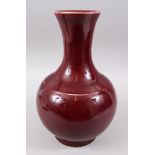 A 19TH / 20TH CENTURY CHINESE OX BLOOD RED PORCELAIN BOTTLE VASE, 33cm high x 20cm wide.
