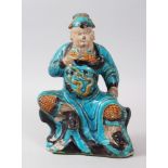 A GOOD CHINESE MING PERIOD TURQUOISE POTTERY FIGURE OF GUANDI, modeled in a seated position upon a