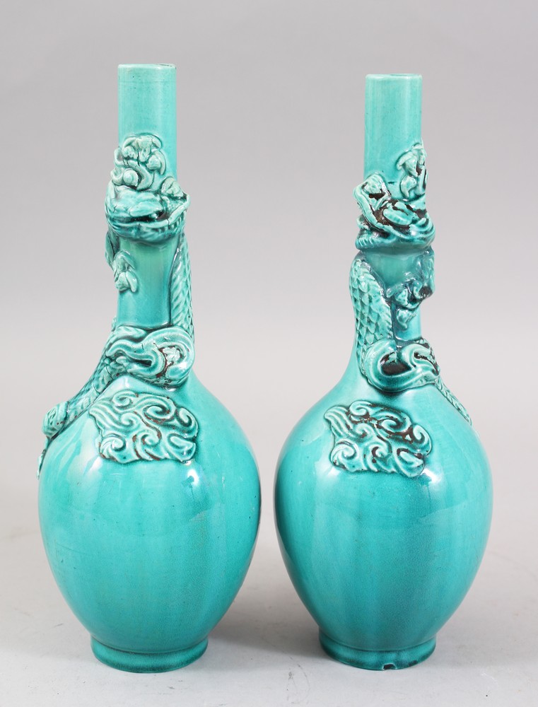 A PAIR OF ORIENTAL TURQUOISE GROUND PORCELAIN DRAGON BOTTLE VASES, both vase with moulded dragons