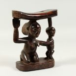 AN AFRICAN TRIBAL HEADDRESS, with carved mother and child support. 19cms high.