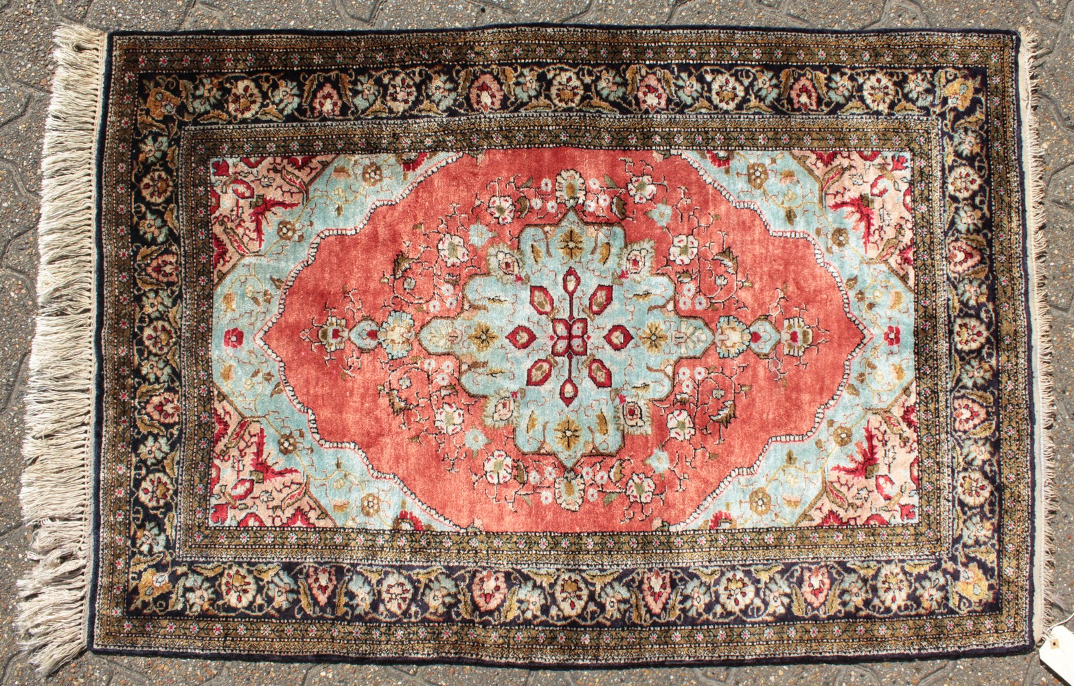 A FINE PERSIAN SILK RUG with central motif on a red background and floral border. 4ft 2ins x 2ft