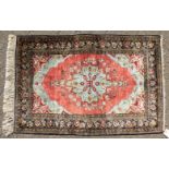 A FINE PERSIAN SILK RUG with central motif on a red background and floral border. 4ft 2ins x 2ft