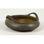 A CHINESE BRONZE CIRCULAR TWO HANDLED CENSER with six character impressed mark. 4ins diameter.