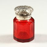 A SMALL VICTORIAN FACET CUT RUBY TINTED GLASS OCTAGONAL SCENT BOTTLE with repousse silver top.