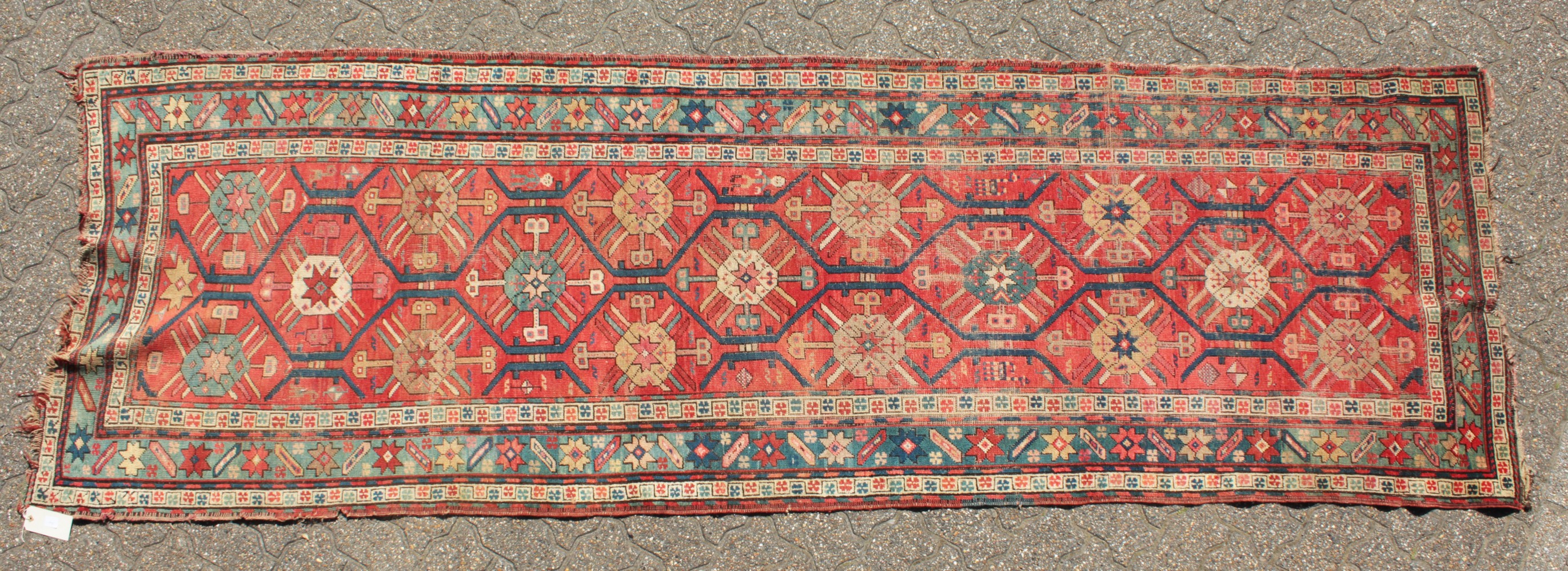 A CAUCASIAN RUNNER with typical motifs in red and blue. 10ft 9ins x 3ft 6ins.