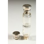 A VICTORIAN DOUBLE ENDED GLASS SCENT BOTTLE, the silver caps engraved with scrolls and with