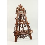 A GOOD 19TH CENTURY BLACK FOREST CARVED WOOD PIERCED EASEL. 66cms high, carved with fruiting vines.