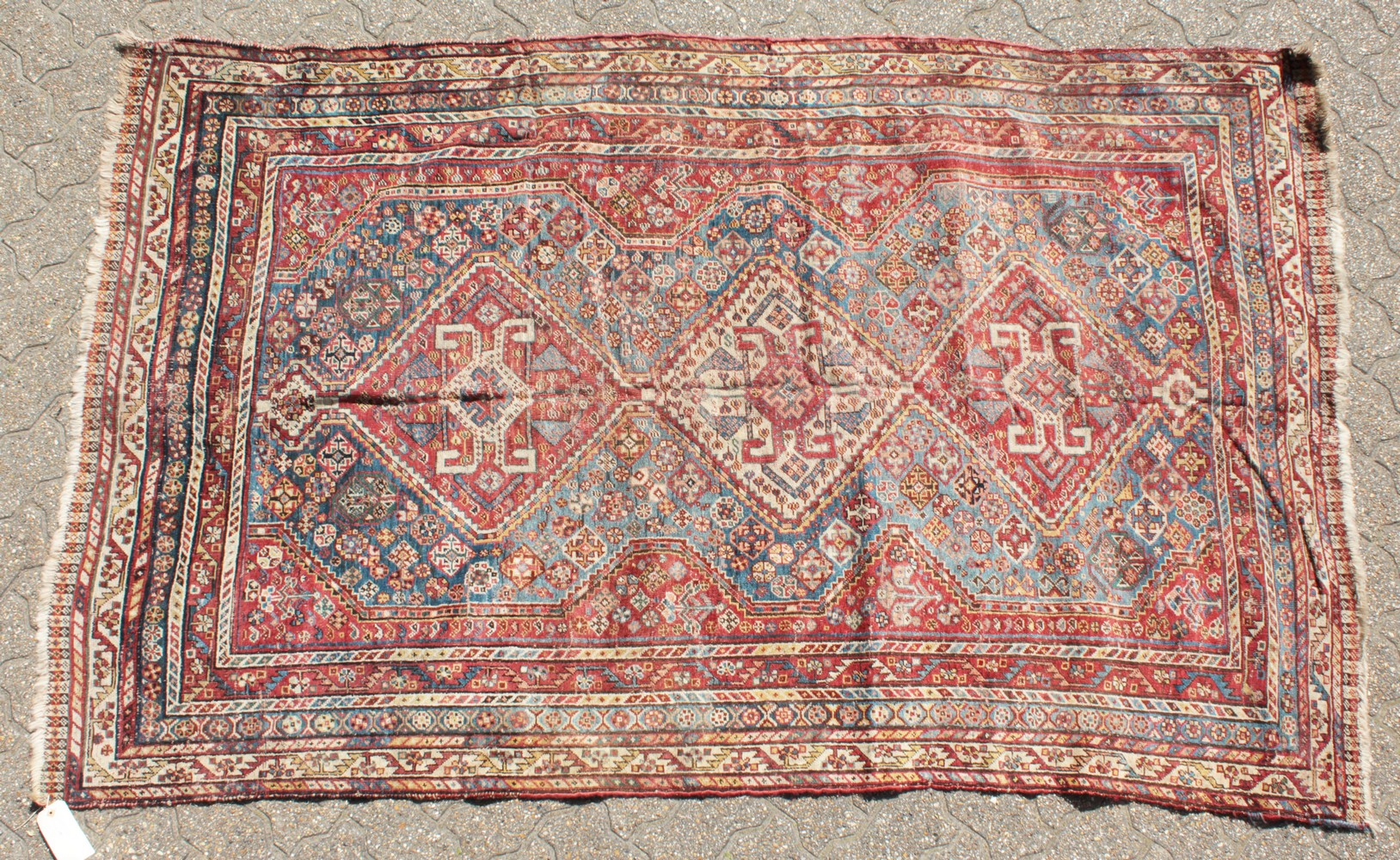 A LARGE OLD PERSIAN SHIRAZ RUG with three main diamond shaped motifs. 7ft 4ins x 4ft 8ins.