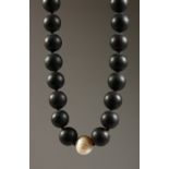A HEAVY BLACK BEAD NECKLACE with a single pearl.