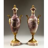 A GOOD PAIR OF VIOLET MARBLE AND ORMOLU MOUNTED VASE SHAPED URNS, each with pineapple finials,