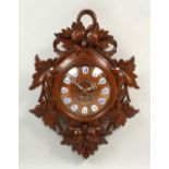 A CARVED OAK BLACK FOREST STYLE WALL CLOCK, with leaf carved decoration and enamel numerals. 64cms