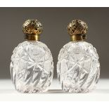 A SUPERB PAIR OF VICTORIAN CUT GLASS CRYSTAL SCENT BOTTLES AND STOPPERS with pierced silver tops.