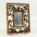 A SMALL FLORENTINE MIRROR, with carved, pierced, gilded and painted frame. 26cms x 21cms.