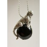 A SILVER ONYX PANTHER PENDANT BROOCH on a chain.