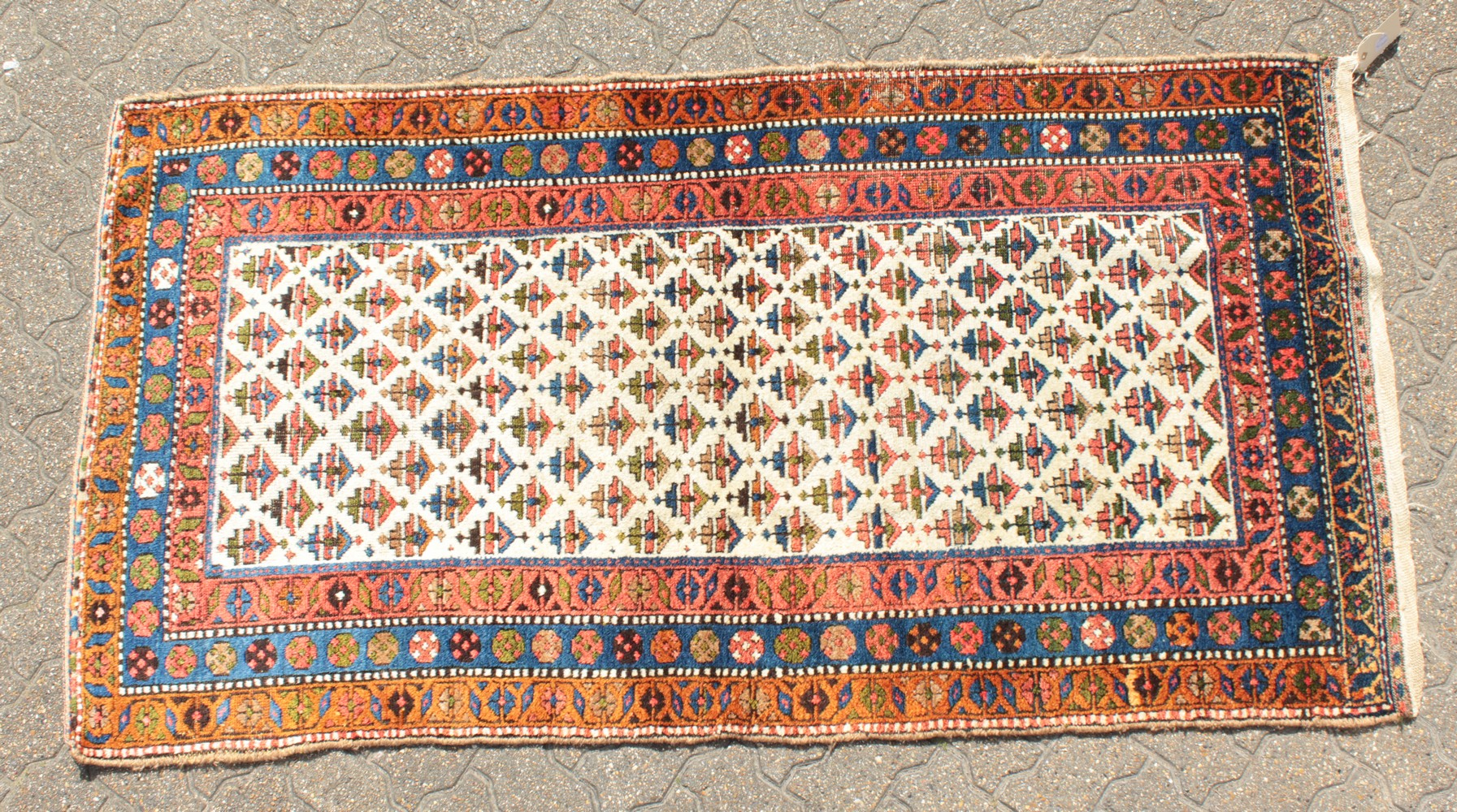 A KURDISH PERSIAN TRIBAL RUG with a key row of motifs on a white ground within a red and blue three