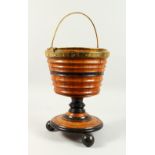 A DUTCH CIRCULAR WOODEN BUCKET ON STAND with brass handle and liner. 1ft 3ins high.