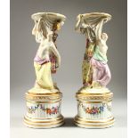 A PAIR OF RUSSIAN PORCELAIN STANDS with circular tops and bases, held by two female figures and