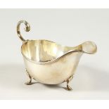 A SAUCEBOAT with reeded edges, scroll handle on three pad feet. Sheffield 1925. Maker Walker and