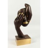 AN ABSTRACT BRONZE OF A FACE AND TWO HANDS. 1ft 6ins high.