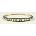 A 9CT GOLD, PERIDOT AND PEARL BANGLE, boxed.