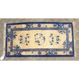 A CHINESE WOOL RUG with three central motifs in blue and cream. 4ft 7ins x 2ft 3ins.