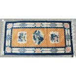 A CHINESE WOOL RUG with three motifs, orange ground with blue and white border. 4ft 6ins x 2ft