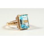 A 14k YELLOW GOLD AND DIAMOND RING set with an emerald cut blue topaz.