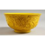 A CHINESE YELLOW CIRCULAR BOWL, the side with dragons in relief. Mark in blue. 6ins diameter.