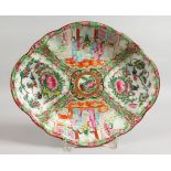 A CANTON OVAL DISH with four panels of birds, butterflies and flowers. 10ins wide.