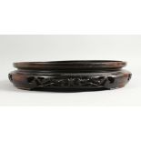 A LARGE CHINESE CARVED AND PIERCED WOOD CIRCULAR VASE STAND. 14ins diameter.