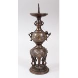 A JAPANESE MEIJI PERIOD BRONZE AND MIXED METAL CANDLE STICK, stood on three shi shi head legs, the